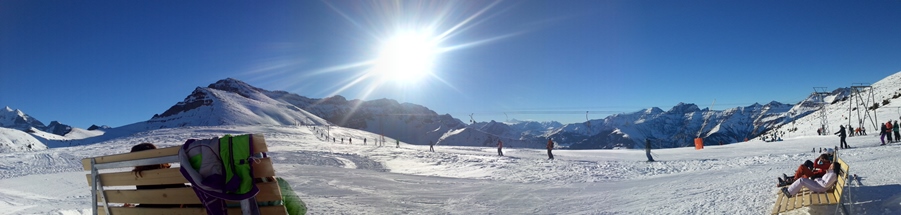 Skilift mit Sonne und Berge im Hintergrund
